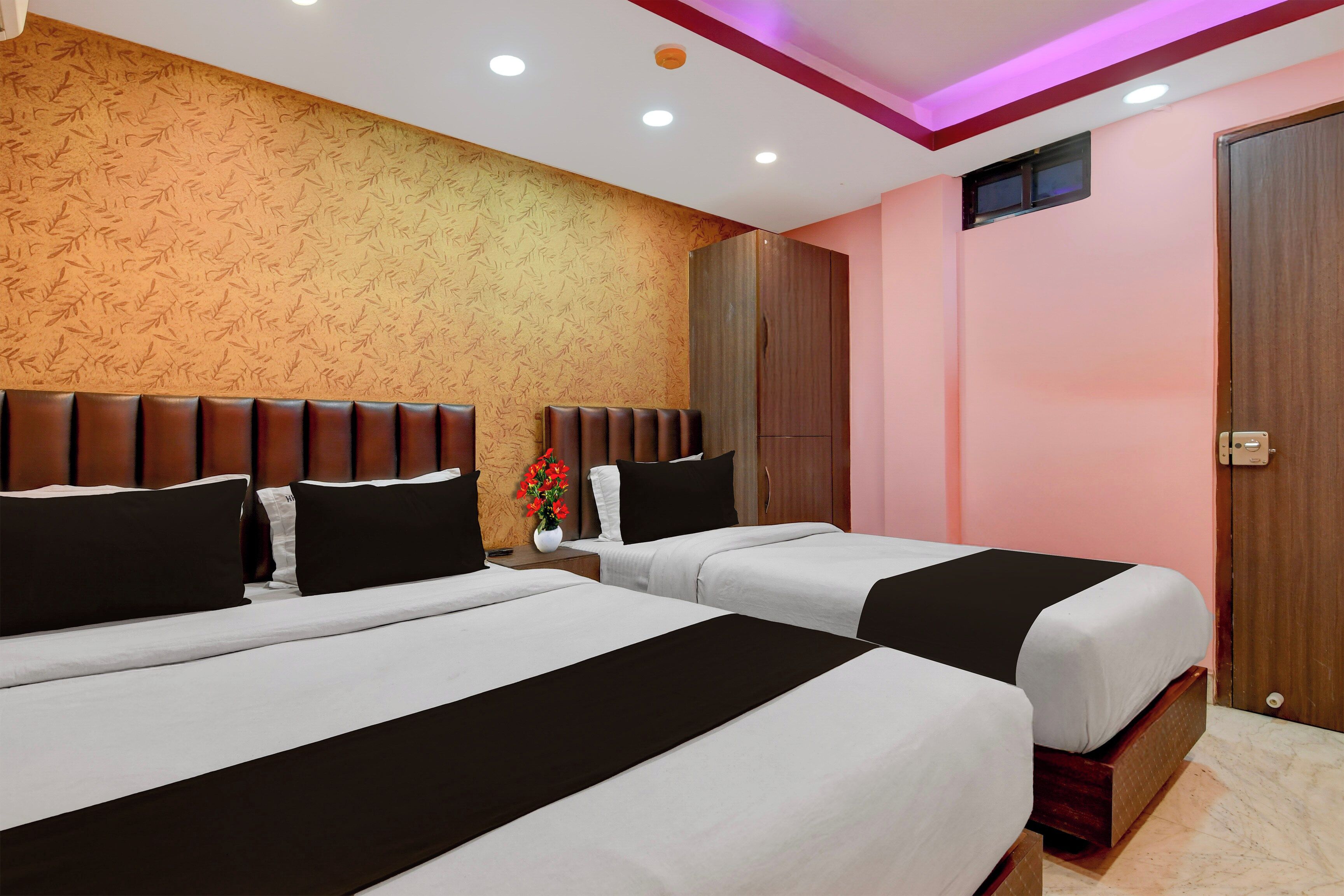 A hotel room with two beds, a wooden headboard, a small window, and a pink wall.