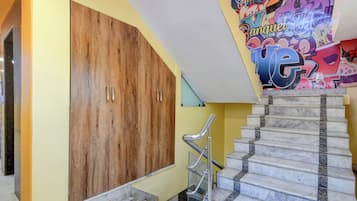 Un escalier avec des marches en marbre et des rampes en métal, menant à une porte en bois dotée de deux poignées.