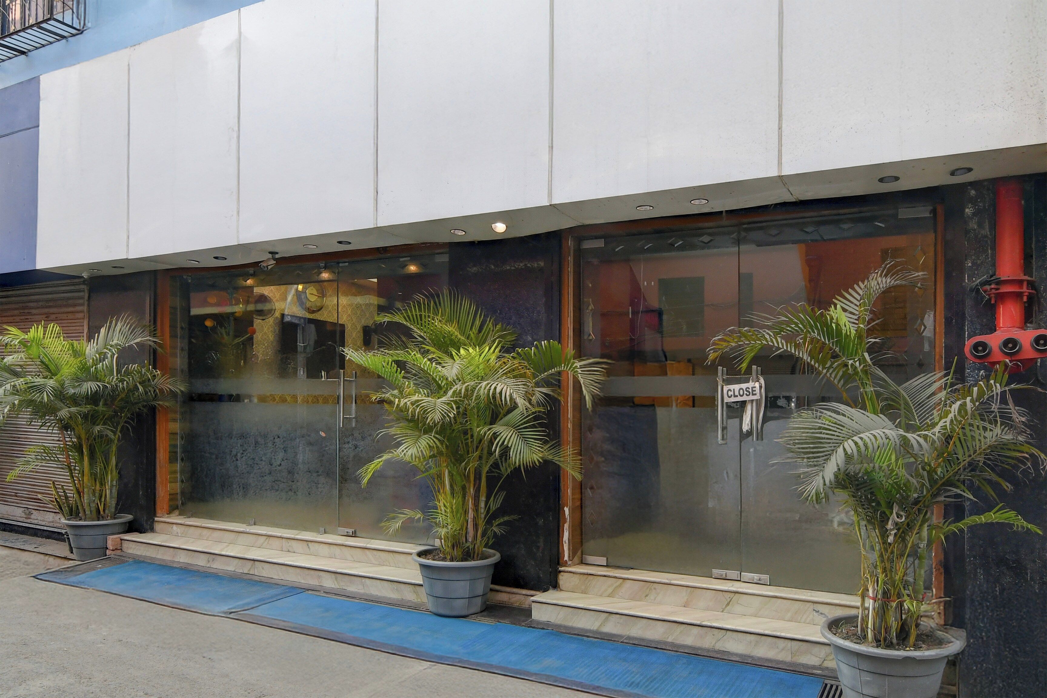 A building with large glass windows, potted plants, and a 'CLOSE' sign on the door.