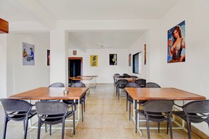 A conference room with multiple tables and chairs, white walls, and various posters. - Super Collection O MIT Alandi (Rajgurunagar)