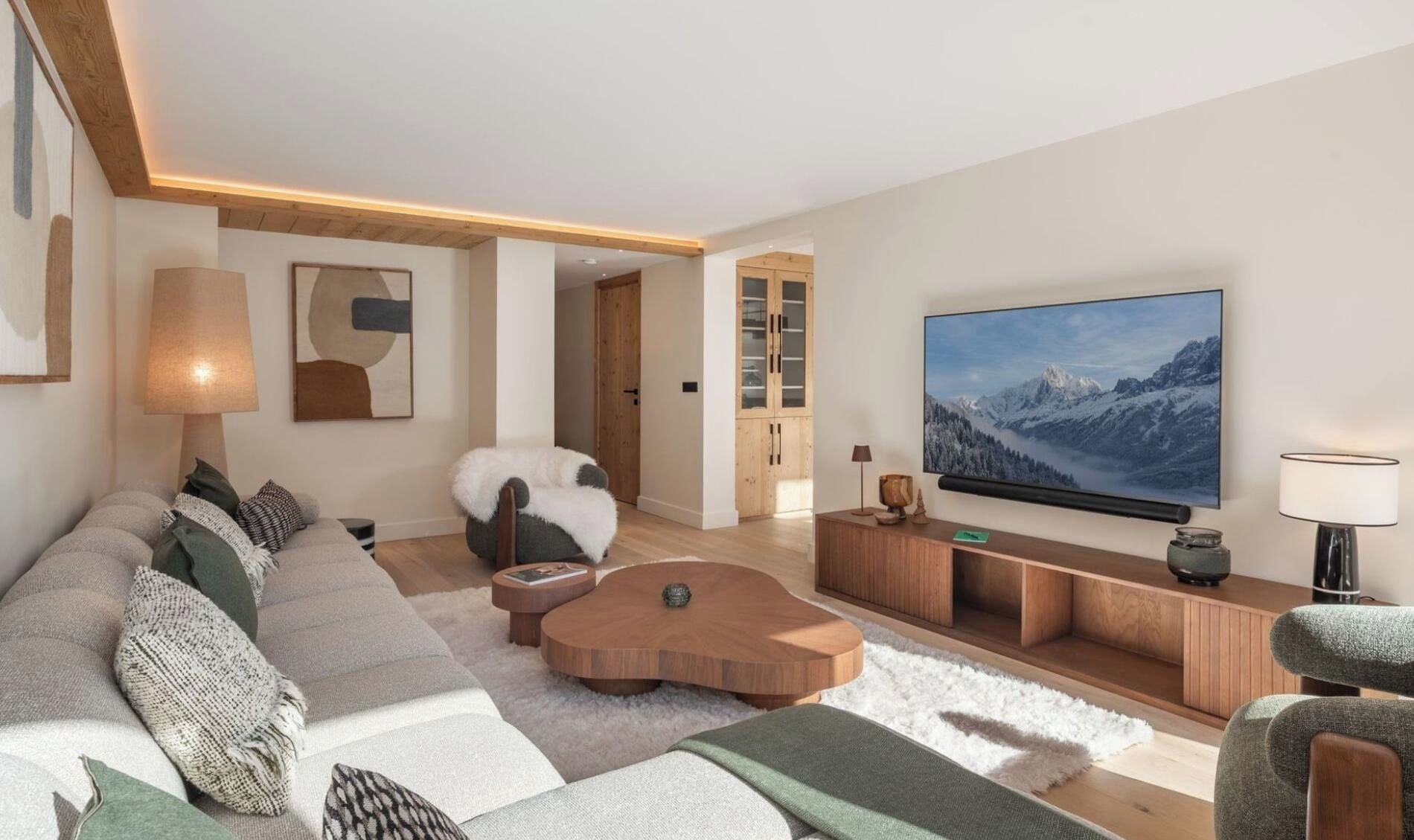 A modern living room with a large flat-screen TV, a sofa set, a coffee table, and a wooden cabinet.