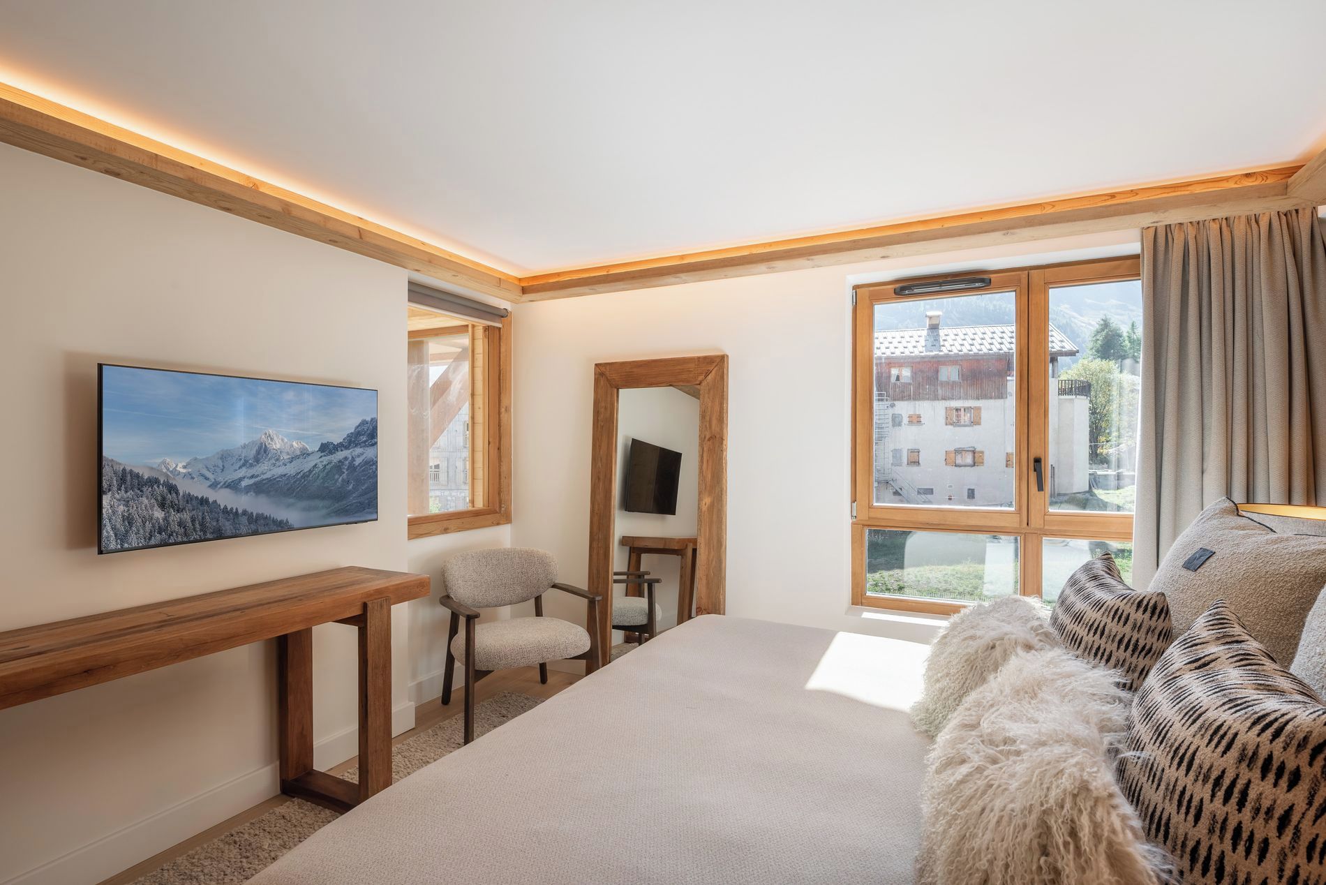 A bedroom with a bed, a desk, a chair, a large window, and a painting.