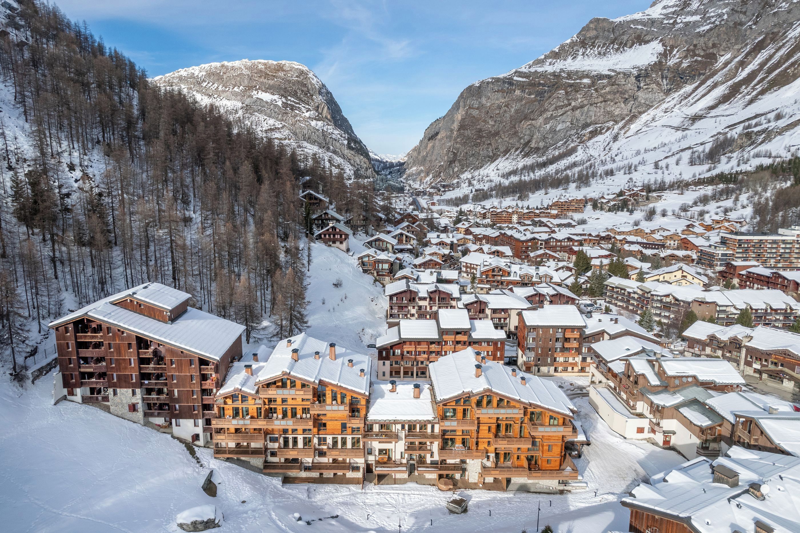 A snow-covered mountain town with wooden buildings and a dense forest.