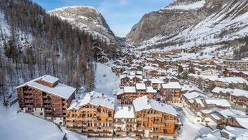 A snow-covered mountain town with wooden buildings and a dense forest.