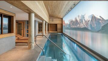 An indoor swimming pool with a mountain mural, wooden beams, and a glass wall.