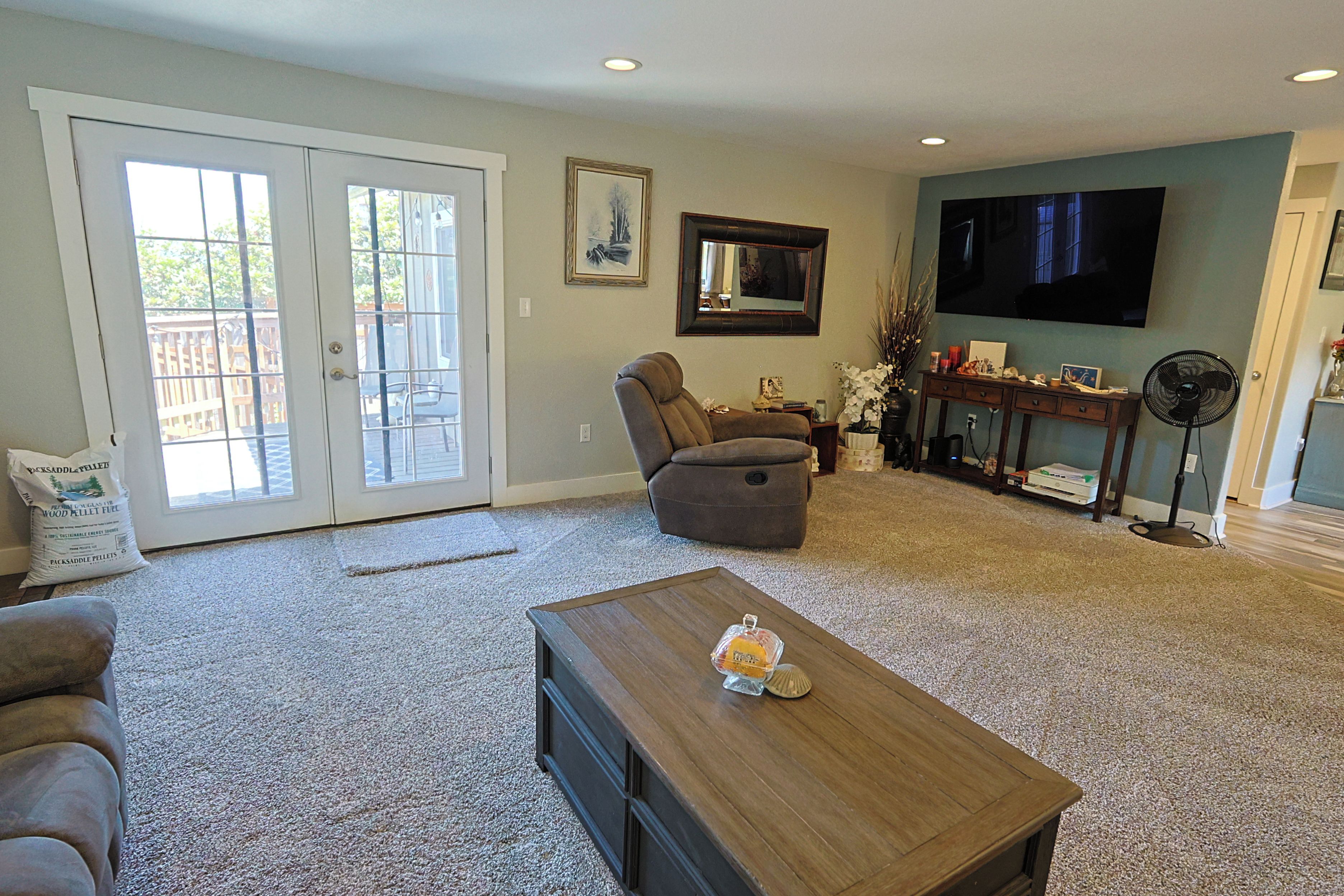 A living room with a sofa, a chair, a coffee table, a TV, and a fireplace.