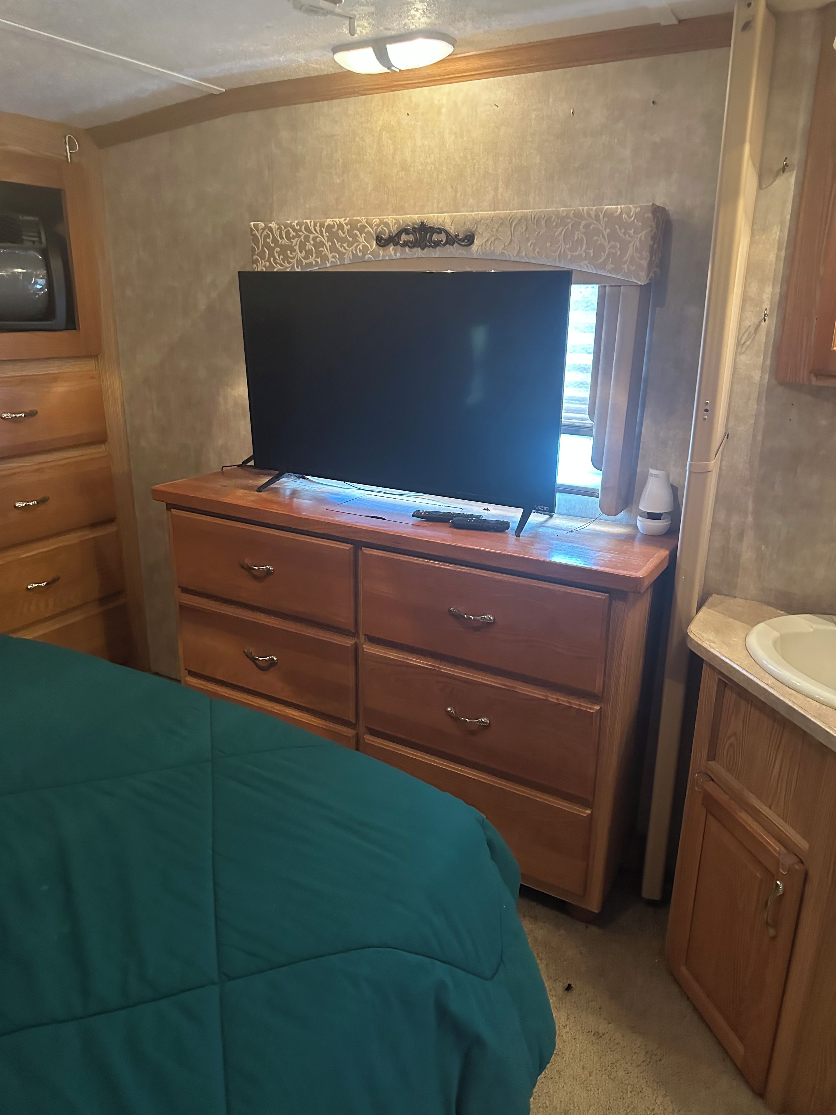 Une chambre à coucher comprenant un lit, une commode, un téléviseur et une salle de bain avec un lavabo.