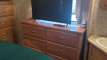 Une chambre à coucher comprenant un lit, une commode, un téléviseur et une salle de bain avec un lavabo.