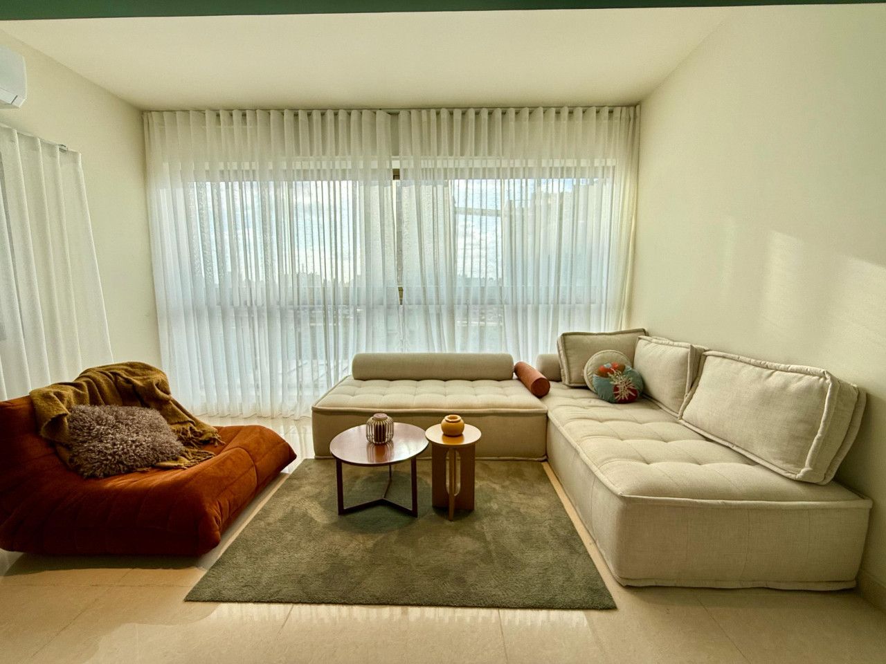 A modern living room with a sofa, a coffee table, and a red armchair.
