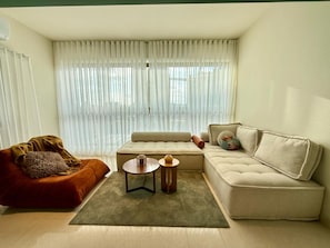 A modern living room with a sofa, a coffee table, and a red armchair. - Riverside Residences by Stayinn (Sin El Fil)