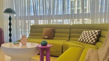 A modern living room with a green sofa, a white coffee table, and a small pink side table.