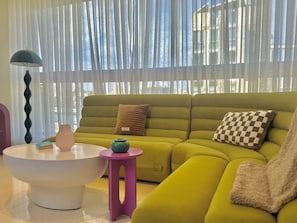 A modern living room with a green sofa, a white coffee table, and a small pink side table. - Riverside Residences by Stayinn (Sin El Fil)