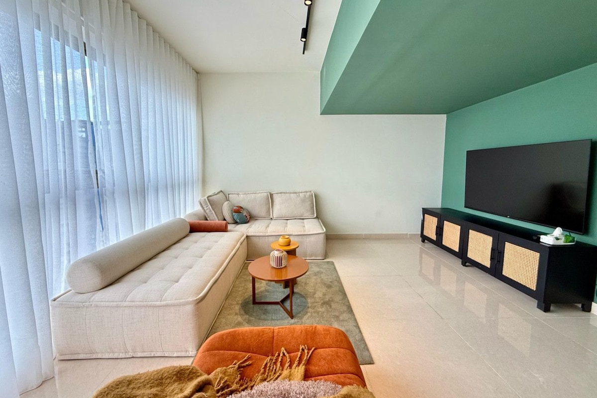 A modern living room with a sectional sofa, a coffee table, and a TV stand.