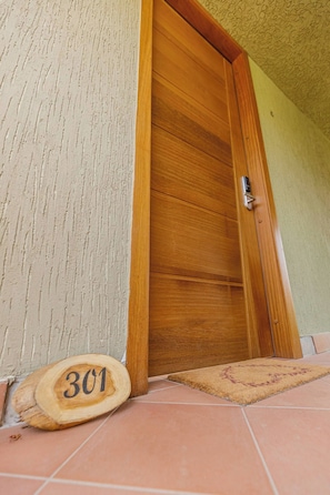 A wooden door with a number plaque, a doormat, and a tiled floor. - Garden suite 301 (Adenta Municipality)