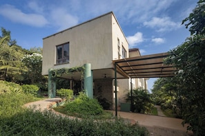 A modern two-story house with a covered patio and lush greenery. - Garden suite 301 (Adenta Municipality)