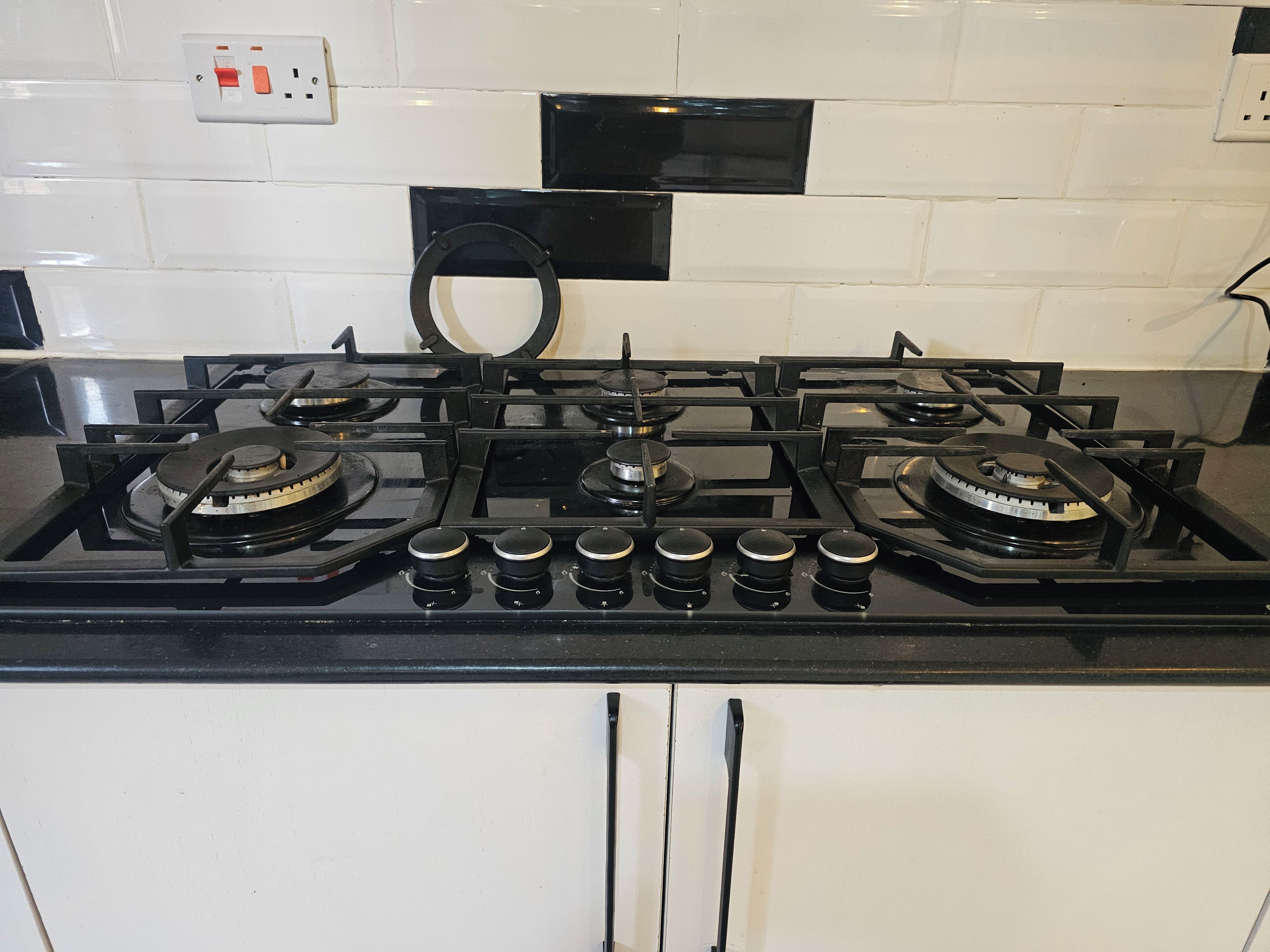 Une cuisine équipée d’une cuisinière à gaz, de quatre brûleurs et d’une hotte aspirante.