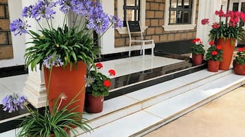 En hotelindgang med en overdækket veranda, plantekasser og et siddeområde.
