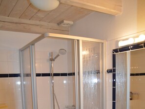 A shower with a glass door, a handheld showerhead, and a wall-mounted faucet. - Hus am a Suud Ferienwohnung Ley (Dunsum)