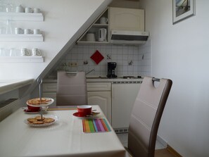 Eine kleine Küche mit Esstisch, Stühlen und einer Kaffeemaschine.