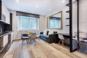 En moderne stue med spiseplads, sofa og et stort spejl.