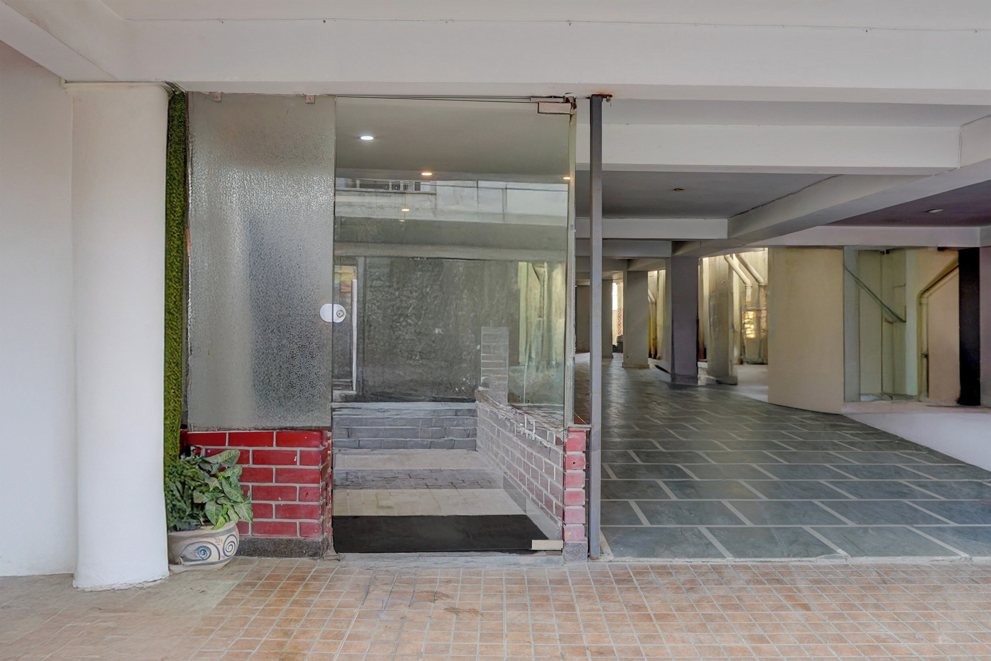 Un pasillo con un piso de baldosas, una puerta de vidrio que da a una escalera, y una planta en maceta.