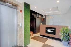 Una zona d'entrada amb un taulell de recepció que porta la inscripció 'TOWNHOUSE OAK' i un senyal que indica 'OYO-Serviced'.