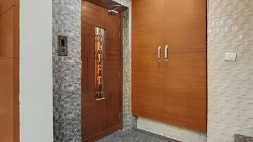An elevator with a stone wall and a wooden door with a decorative panel.