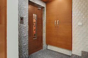 Un ascensor con pared de piedra y puerta de madera con un panel decorativo.
