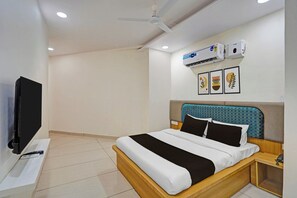 A hotel room with a bed, a TV, an air conditioning unit, and a ceiling fan.