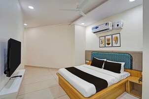 A hotel room with a bed, a TV, an air conditioning unit, and a ceiling fan.