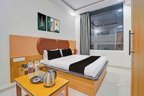 A hotel room with a bed, a table with a kettle, and a window with curtains. - Townhouse Oak Sun City Mall Hisar (Hisar)