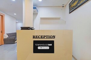 A reception desk with a sign indicating 'RECEPTION' and 'TOWNHOUSE OAK' with a logo for 'OYO-Serviced'.