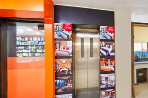 An elevator with 24/7 open signage, surrounded by various hotel room images.