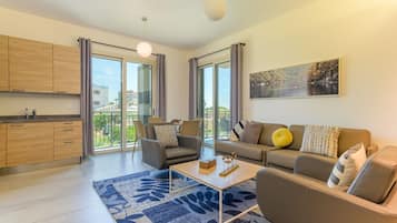 Una sala moderna con un sofá, sillones, una mesa de centro y un amplio ventanal con vistas al exterior.