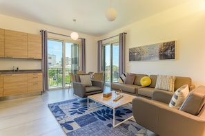 Una sala moderna con un sofá, sillones, una mesa de centro y un amplio ventanal con vistas al exterior.