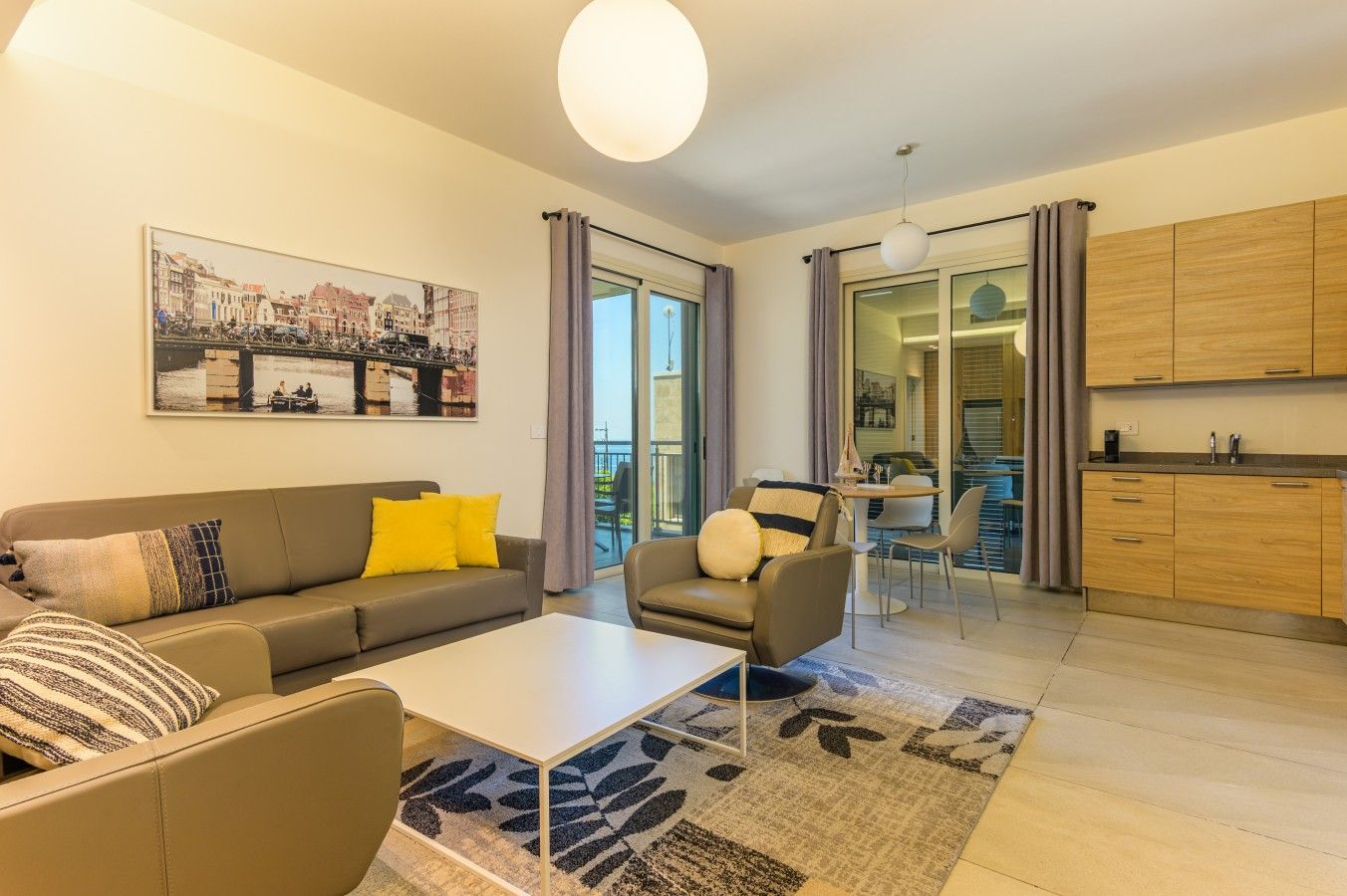 Un salon moderne avec un canapé, un fauteuil, une table basse et une vue sur la ville grâce à de grandes fenêtres.