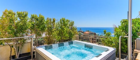 A hot tub on a deck with a view of the ocean.