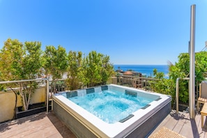 A hot tub on a deck with a view of the ocean.