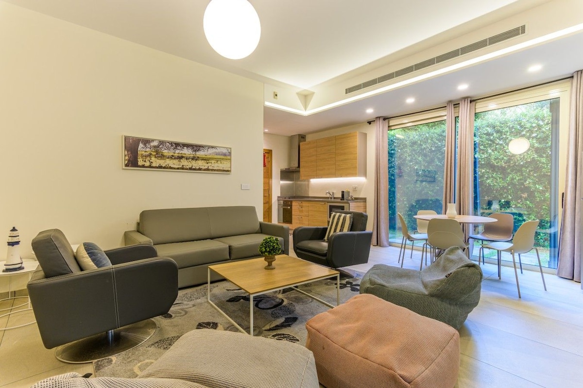 Una sala moderna con un sofá, sillones, una mesa de centro y un comedor con sillas y una mesa.