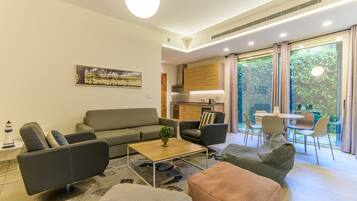 Ein modernes Wohnzimmer mit einer Couch, Sesseln, einem Couchtisch und einem Essbereich mit Stühlen und Tisch.