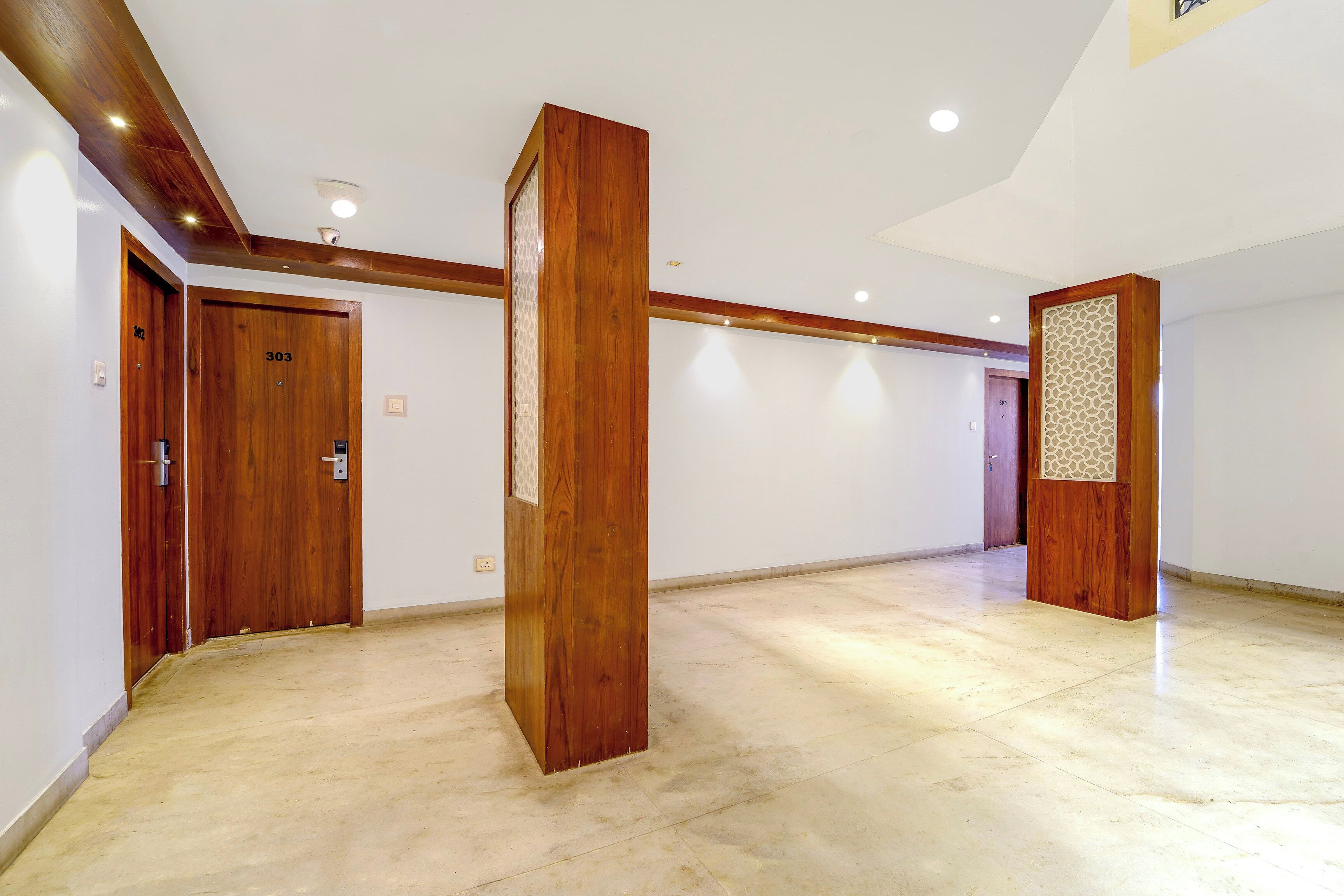 Un hall d’entrée spacieux, doté de portes en bois, d’un pilier central et d’un mur décoratif à motifs.