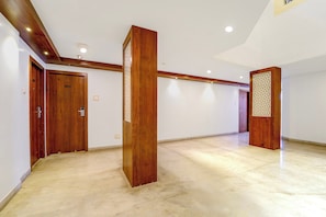 Un pasillo amplio con puertas de madera, un pilar central y un diseño decorativo en la pared.