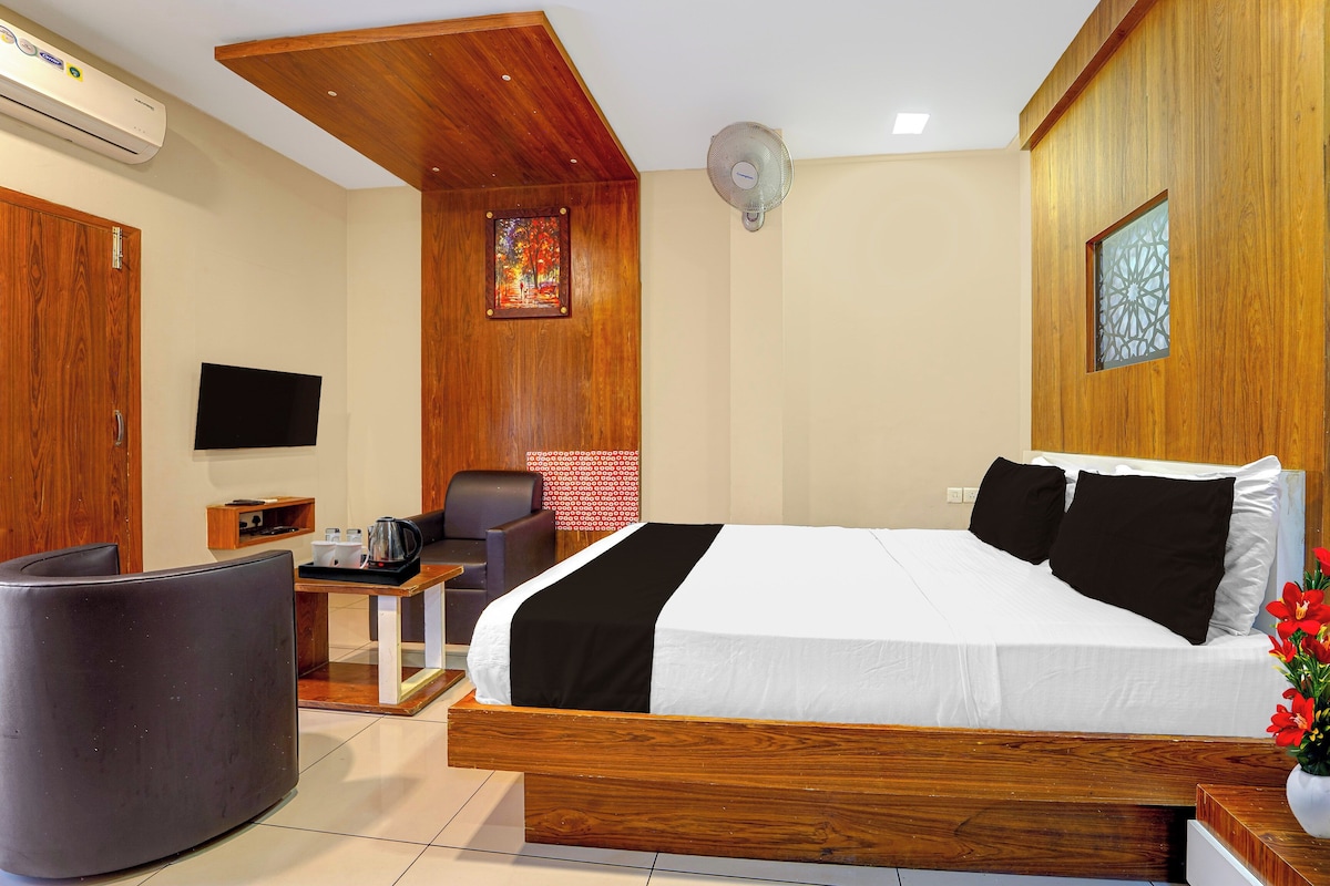 A hotel room with a bed, a desk, a chair, a TV, and a wall-mounted air conditioner.
