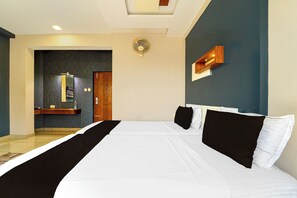 A hotel room with a large bed, a built-in desk, a mirror, and a wall-mounted fan. - Townhouse Oak Kozhikode Bus Stand (Kozhikode)