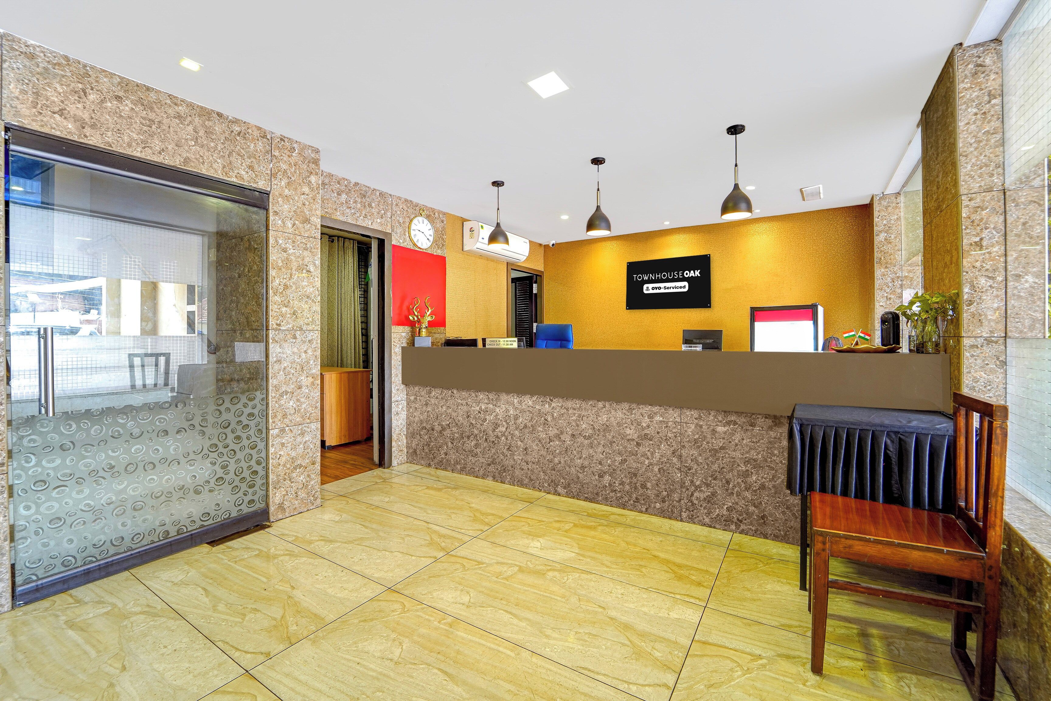 Een hotel receptie met een marmeren balie, een klok en een bord met de tekst 'Townhouse Oak' en 'OYO-Serviced'.