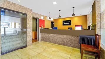 Een hotel receptie met een marmeren balie, een klok en een bord met de tekst 'Townhouse Oak' en 'OYO-Serviced'.