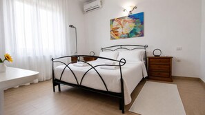 Une chambre à coucher avec un lit, des tables de chevet, une commode, un bureau et un tableau au mur.