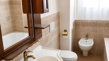 Un bagno con lavandino, WC, bidet e specchio.