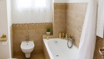 Et badeværelse med badekar, bidet og toilet.