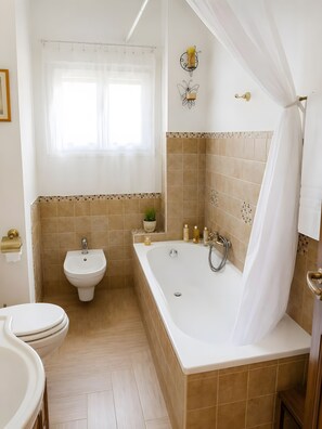 A bathroom with a bathtub, bidet, and toilet.
